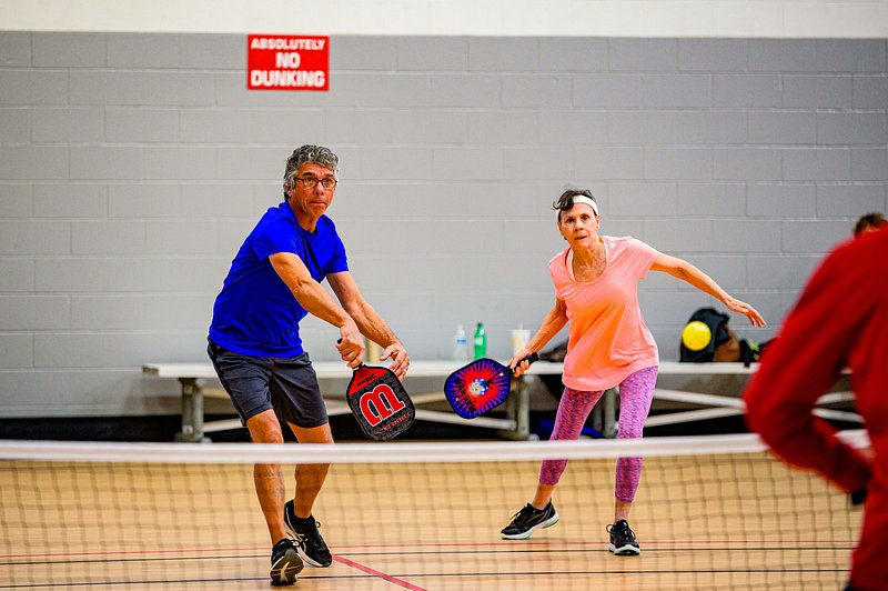 Two players at the kitchen line in an indoor doubles game